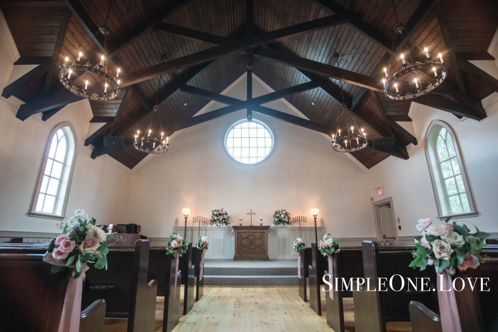 Timber trusses and chandeliers over a chapel set for a ceremony.