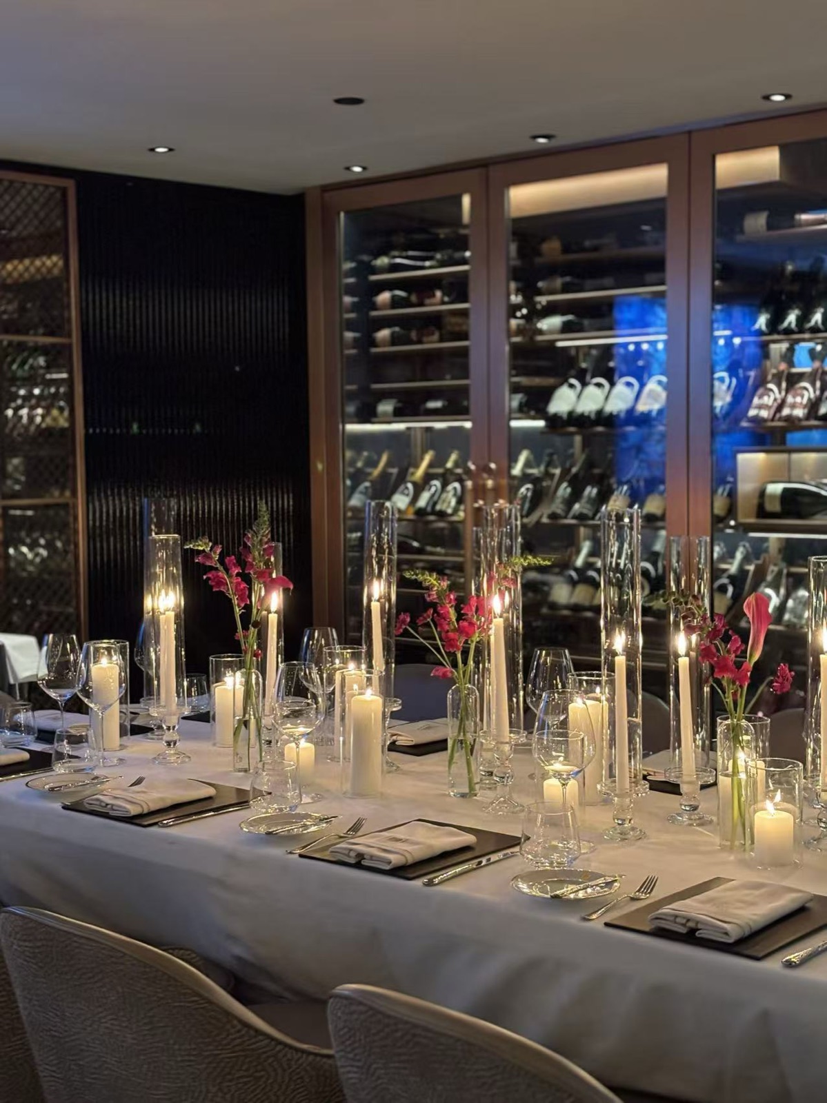 Candles and a wine wall in a dark private dining room.