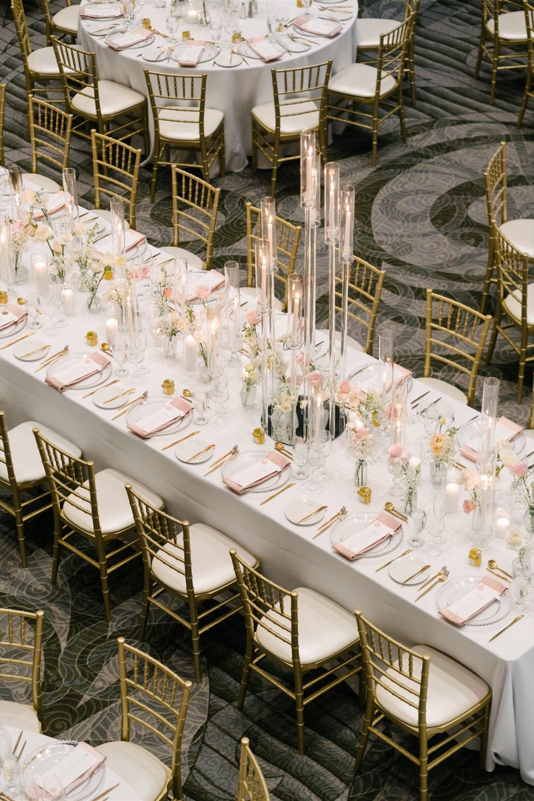 A long banquet table of candles and bud vases.