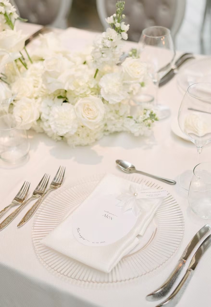 A place setting with a folded menu and white roses.