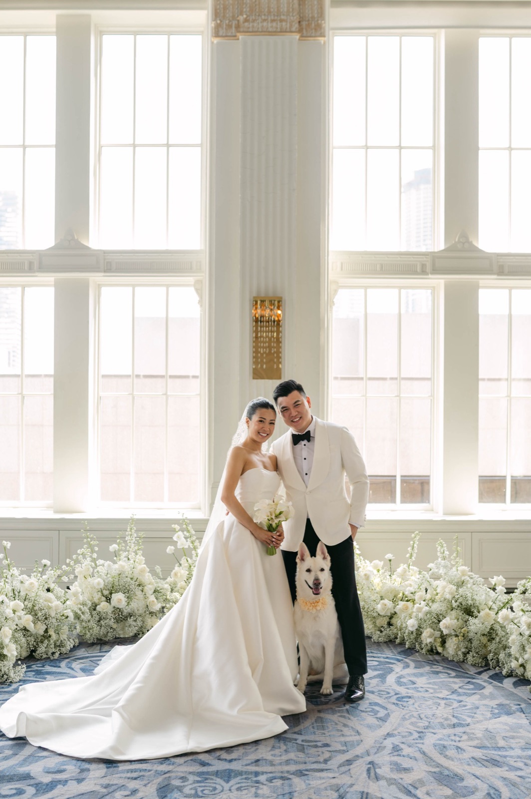 A couple in window light, a small dog at their feet.